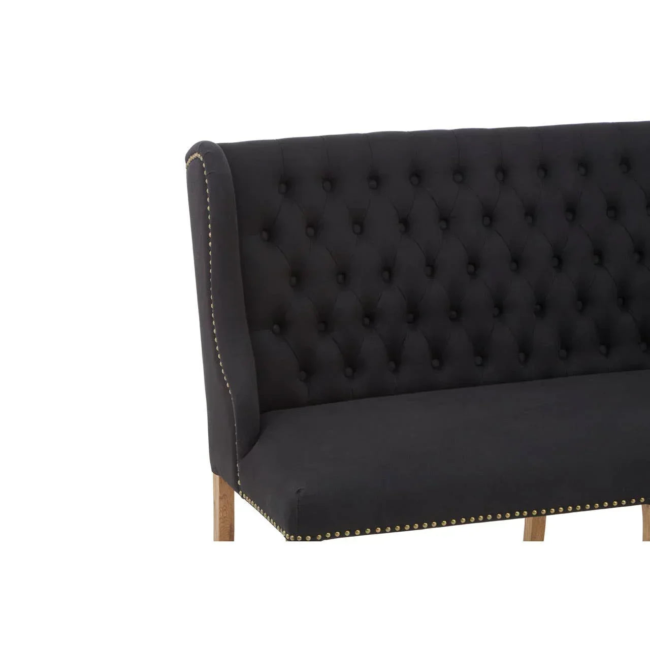 Black upholstered dining bench with button-tufted back and gold nailhead trim
