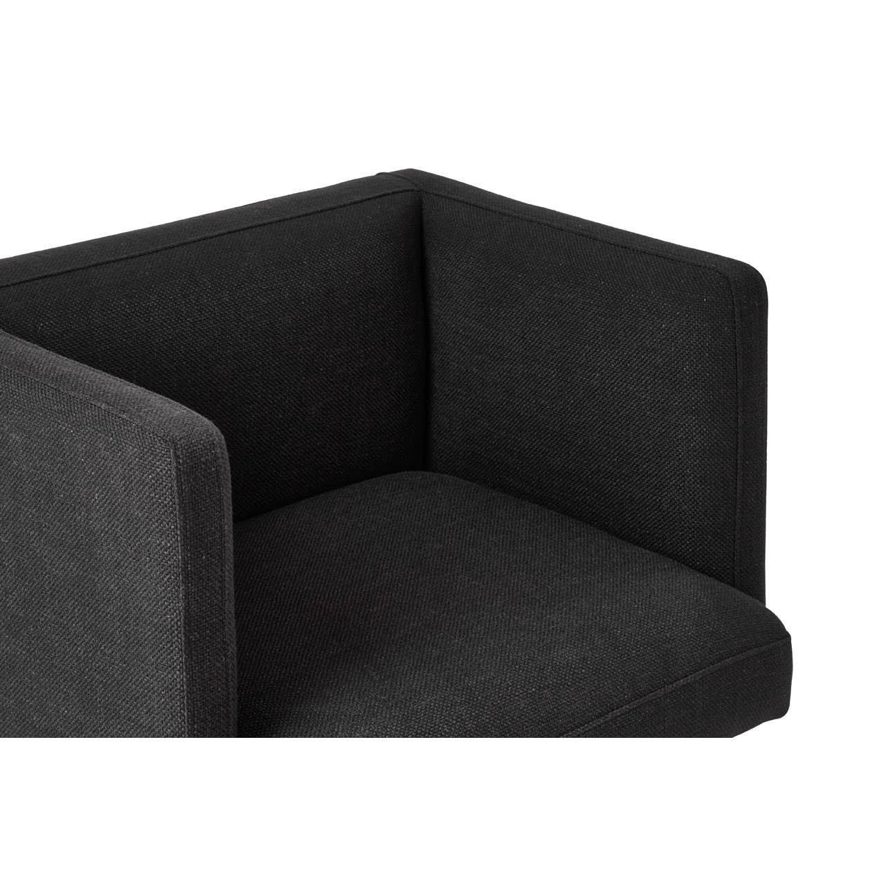 Close-up of black fabric armchair corner with clean, square lines and textured upholstery