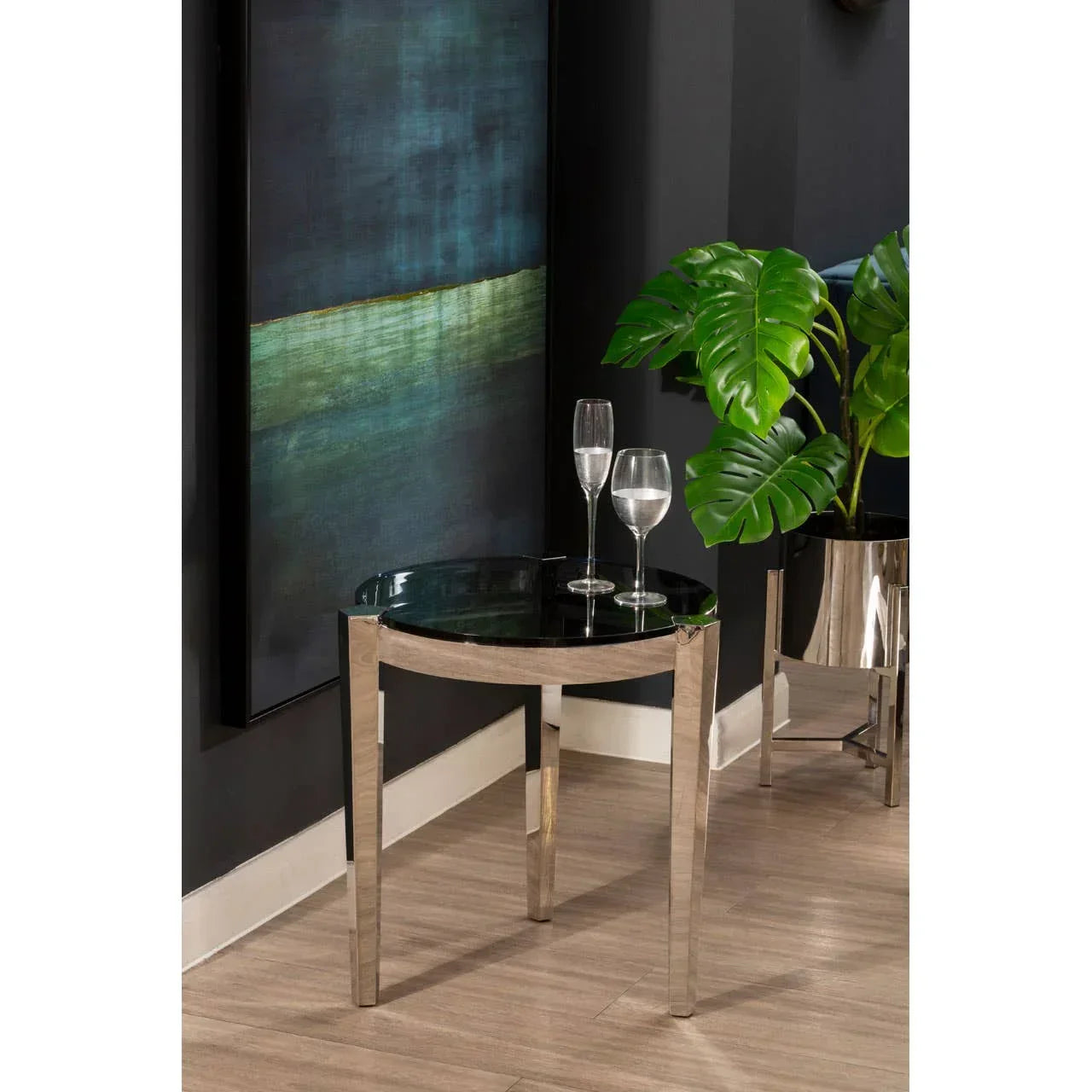 Round glass top side table with chrome legs, two glasses, modern decor, indoor setting