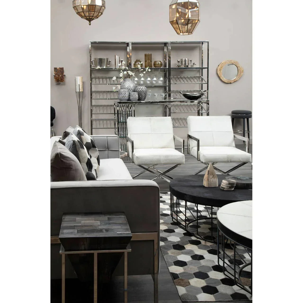 Modern living room with white accent chairs, grey sofa, geometric rug, and metallic shelves