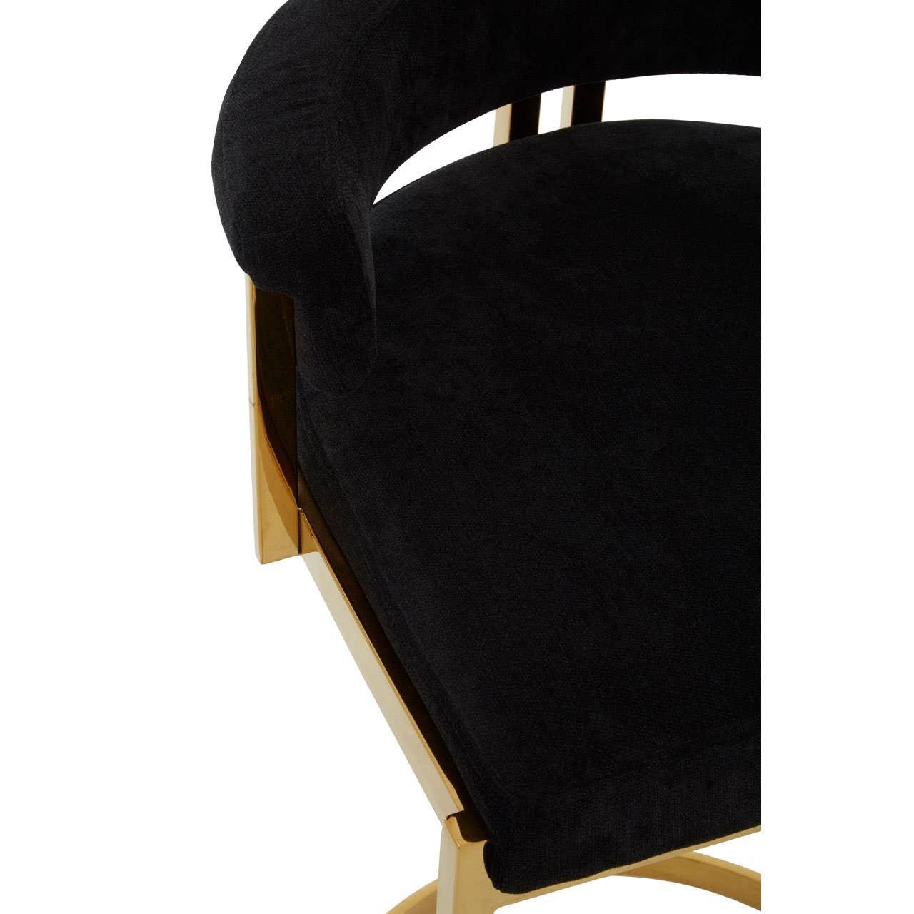 Black velvet upholstered chair with curved seat and gold metal frame, close-up angle