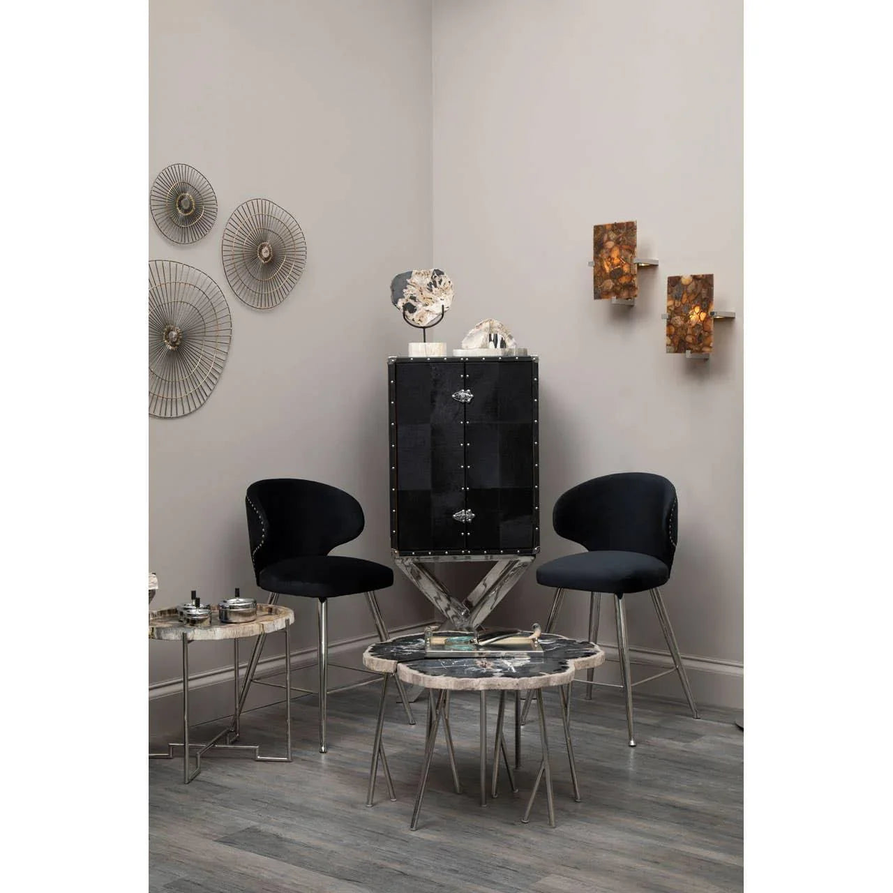 Modern living room with black accent chairs, marble side tables, and metal display cabinet