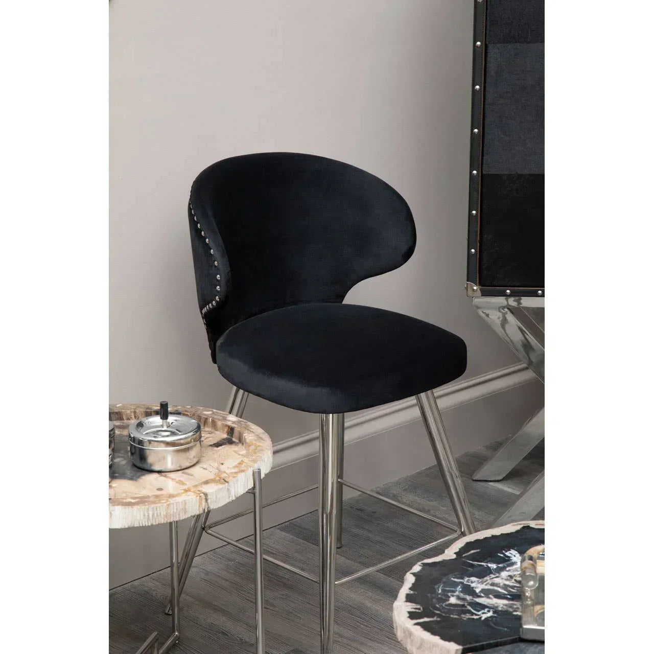 Black velvet dining chair with metal legs beside marble-effect tables in modern interior