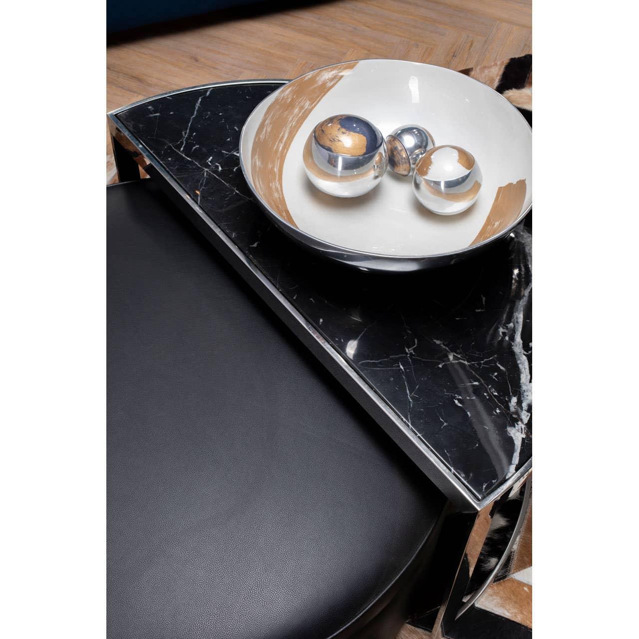Black marble side table with decorative bowl and metallic spheres on wooden floor