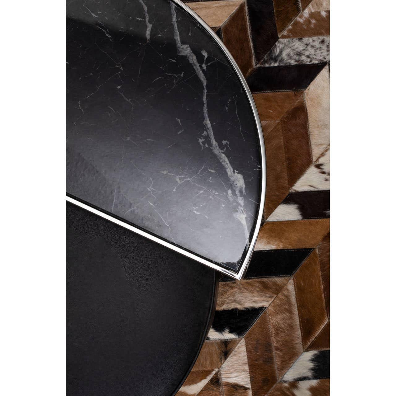 Black marble coffee table with metal trim on geometric cowhide rug