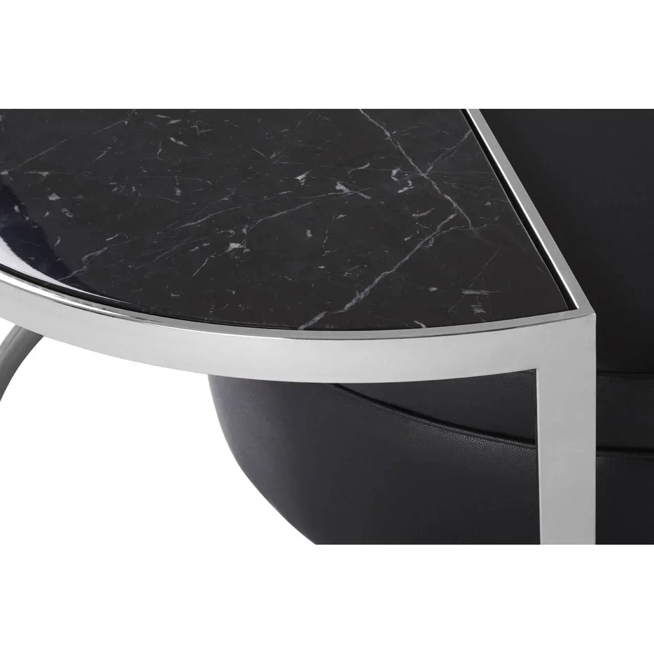 Round coffee table with black marble top and chrome metal frame, close-up corner view