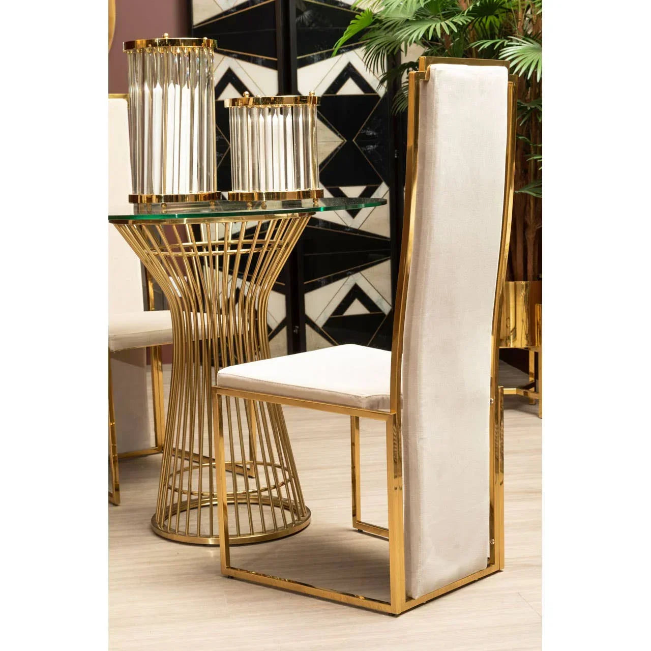 Gold metal dining chair with white upholstery beside round glass dining table