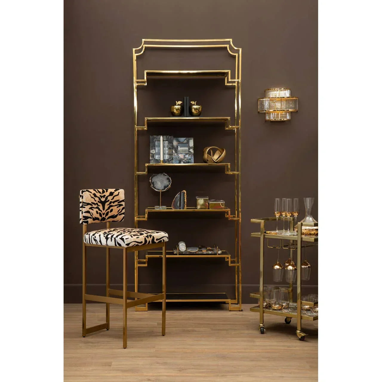 Gold metal shelving unit with glass shelves, zebra print bar stool, bar cart and glassware