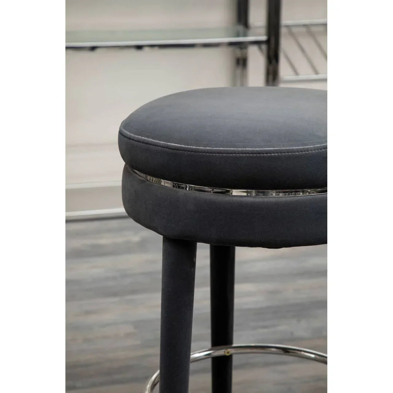 Grey upholstered bar stool with chrome leg detail on wooden floor