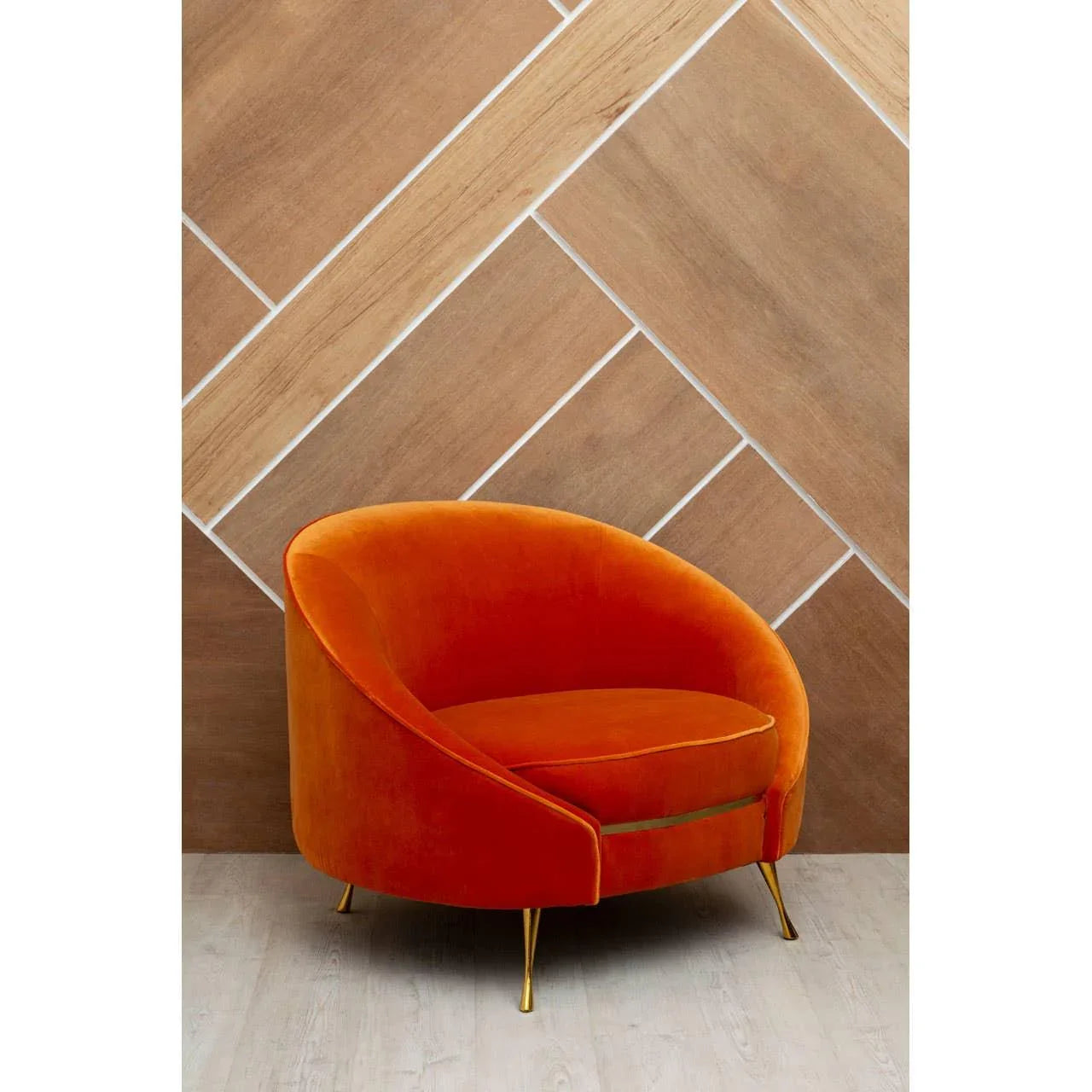 Orange velvet accent chair with gold legs on light wood floor