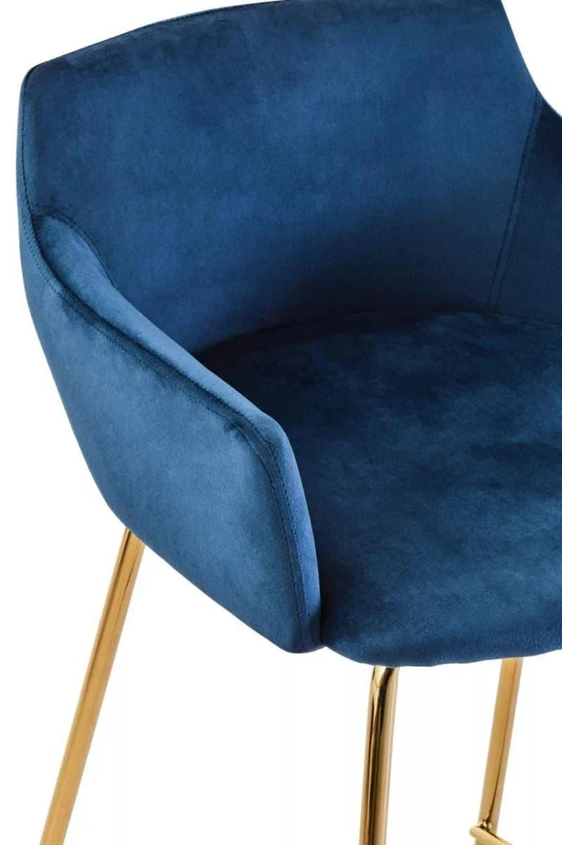 Blue velvet dining chair with curved backrest and gold metal legs, close up view