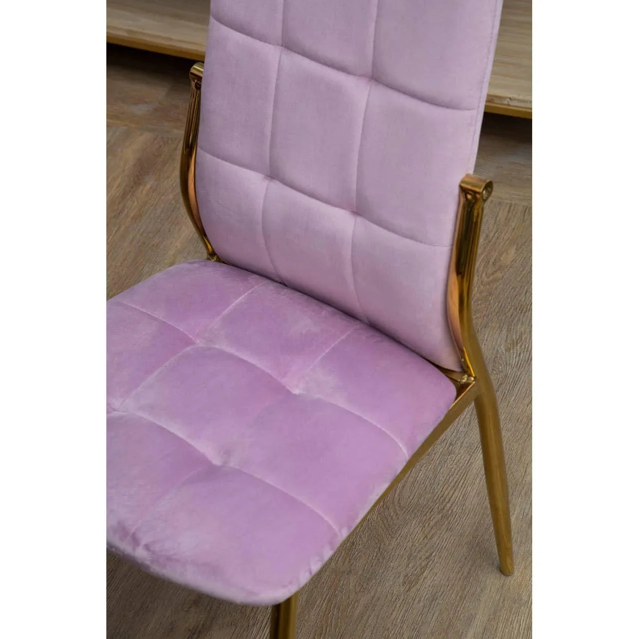 Pink velvet dining chair with gold metal frame on wood floor