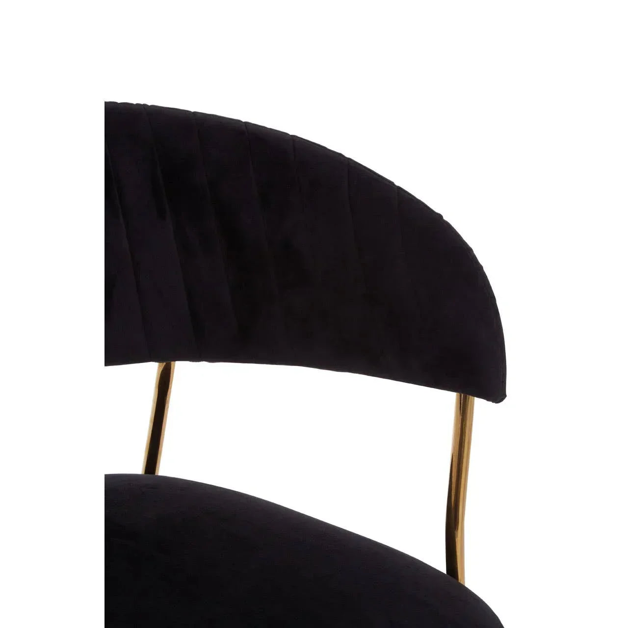 Close-up of black velvet dining chair with gold metal legs and curved backrest