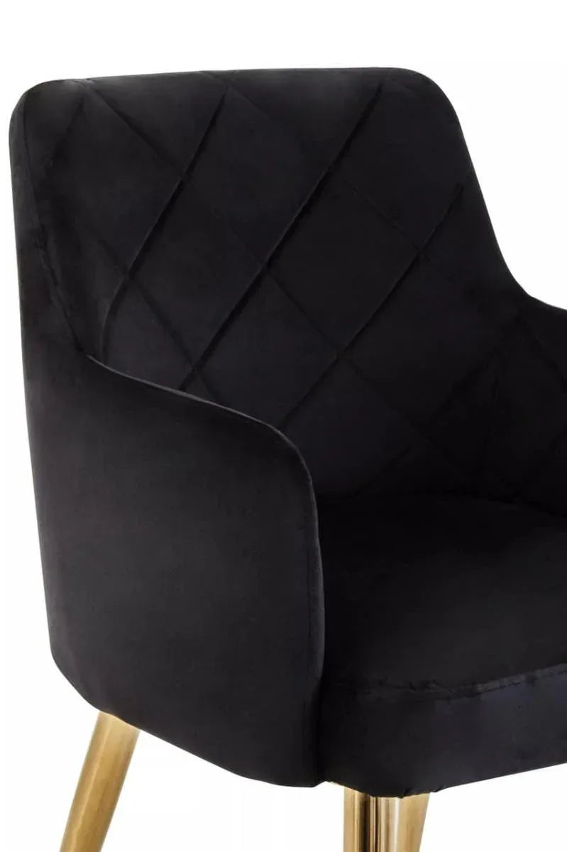 Black velvet dining chair with quilted backrest and gold metal legs, close side view
