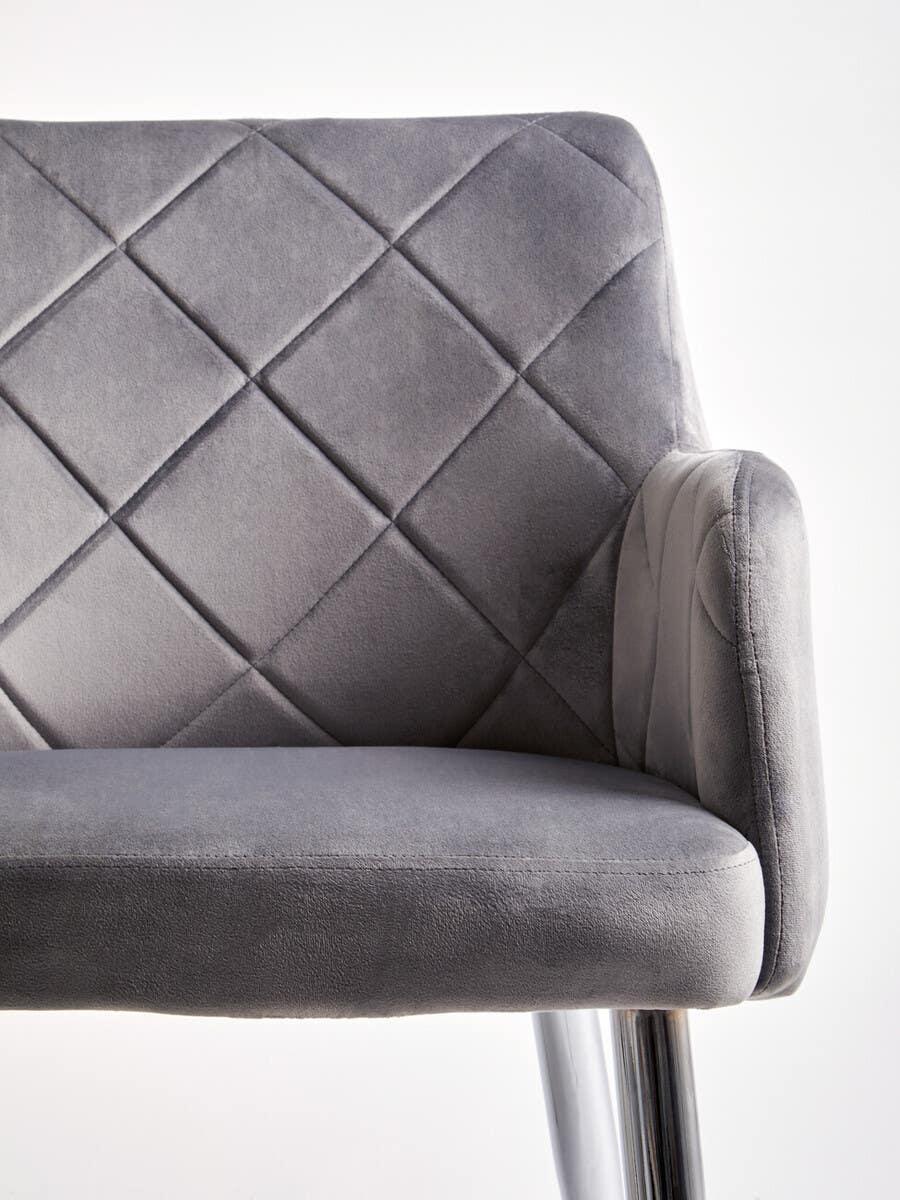 Grey velvet dining chair with chrome legs and diamond stitched backrest, side angle view