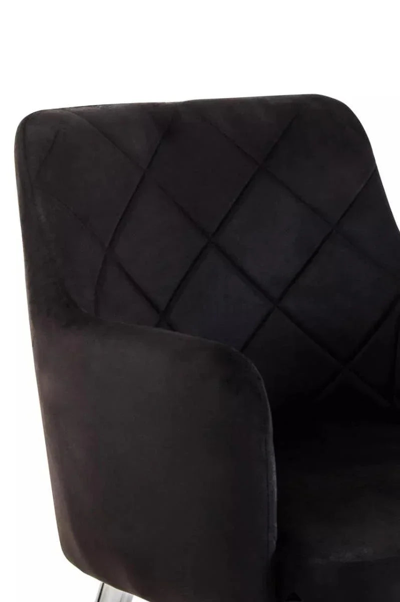 Black velvet dining chair with diamond-stitched backrest and curved arm detail