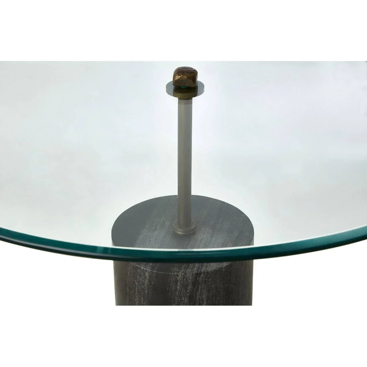 Closeup of glass dining table with metal support and marble-effect cylindrical base