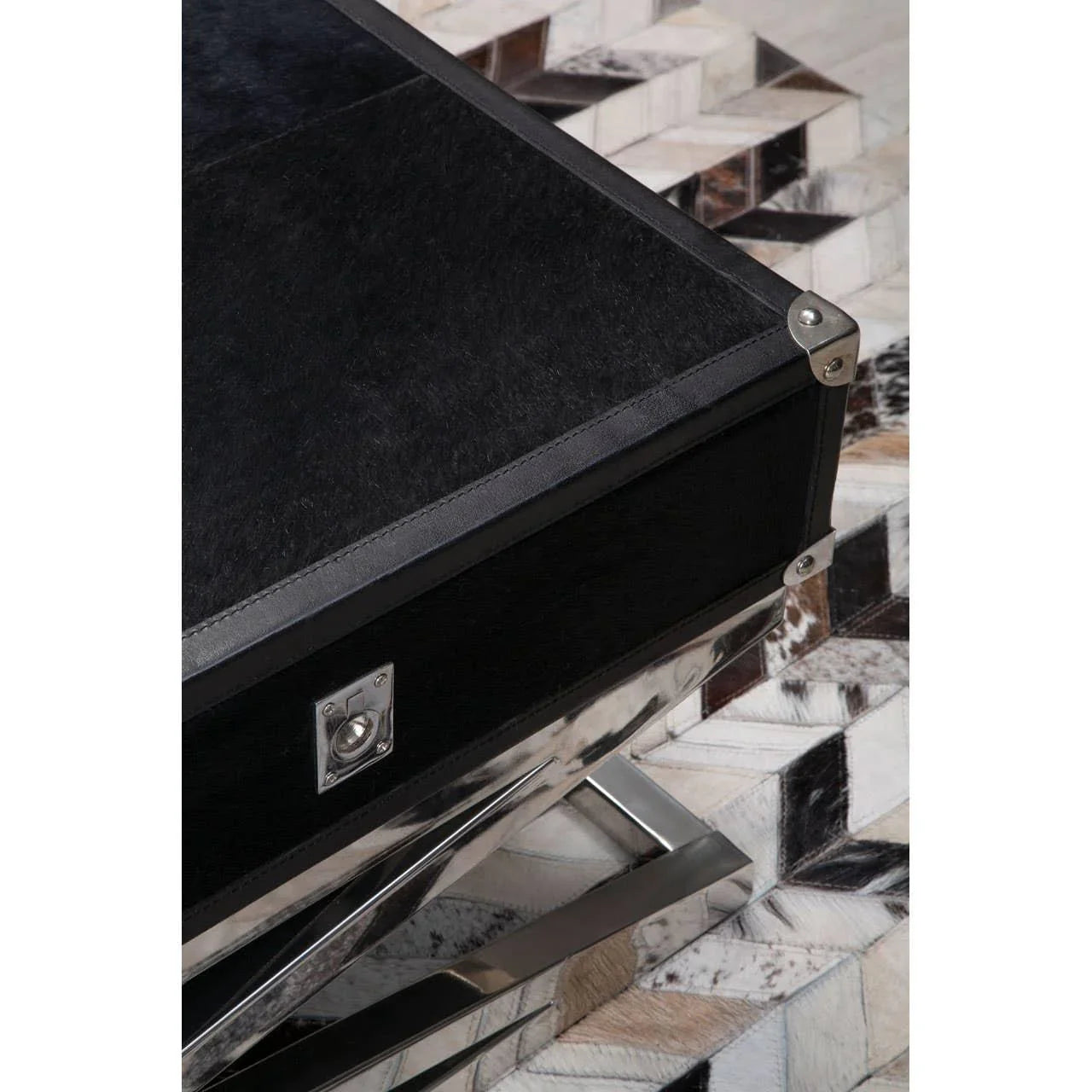 Black storage trunk with metal trim and corner accents on geometric patterned rug