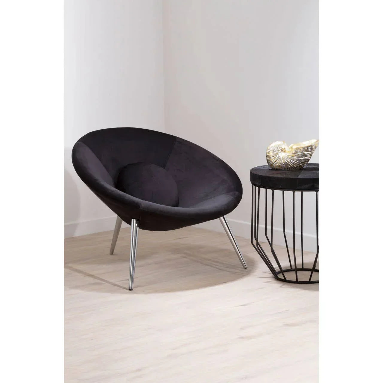 Black accent chair with round seat and chrome legs beside modern black side table