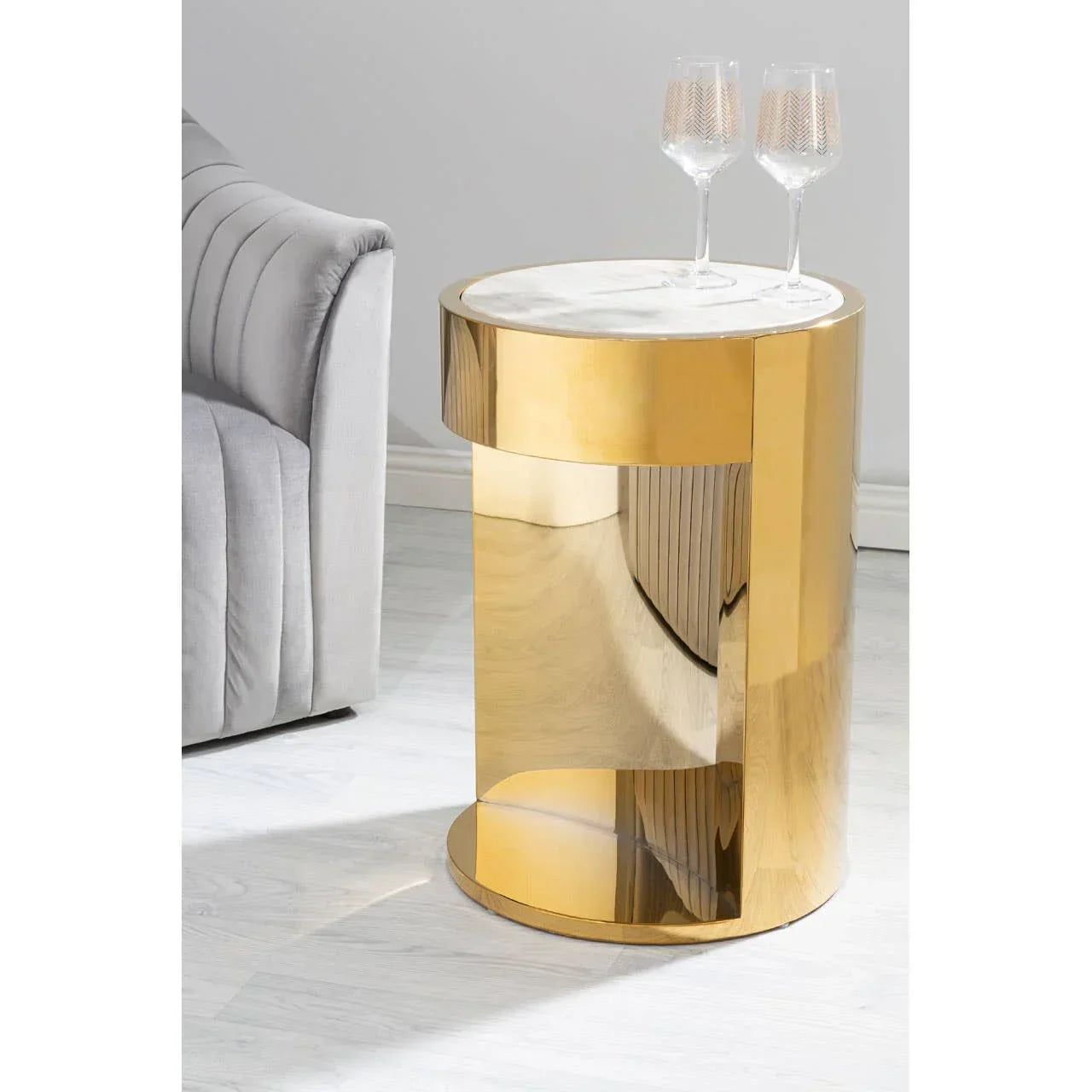 Gold side table with marble top beside grey sofa, two glasses placed on table surface