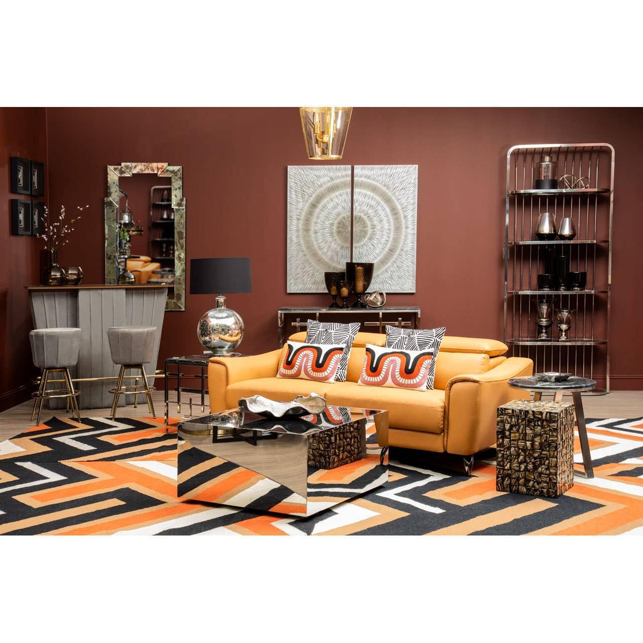 Modern living room with tan leather sofa, geometric rug, mirrored coffee table, and bar stools