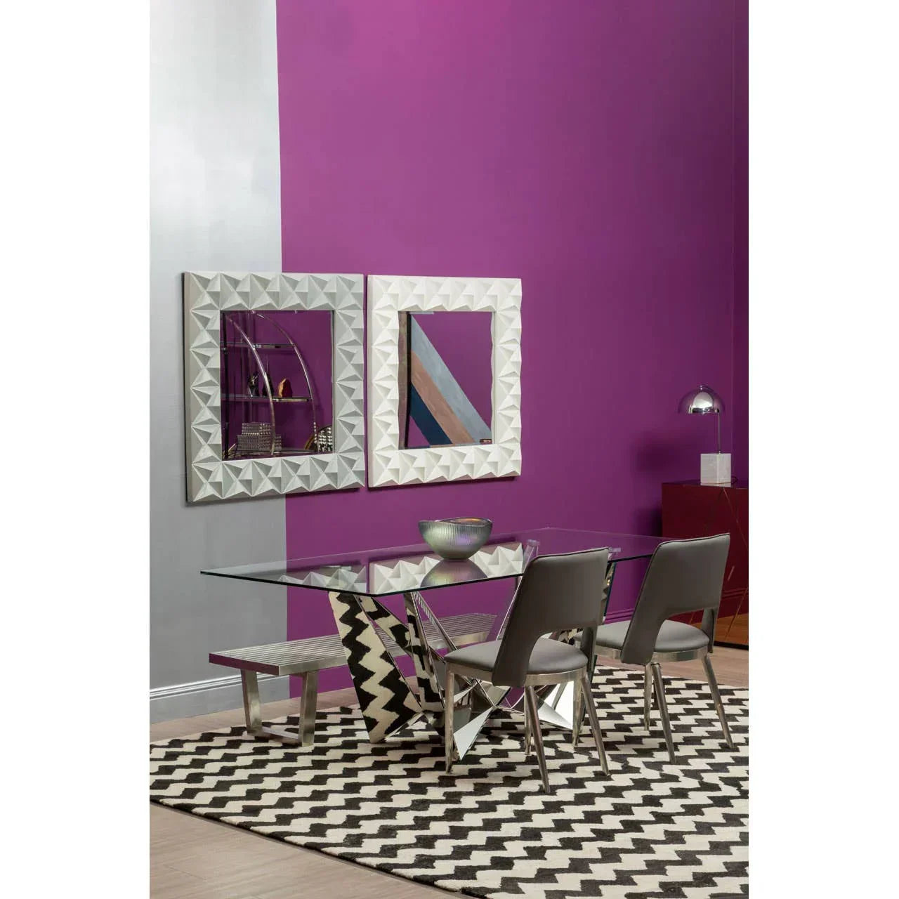 Glass dining table with geometric metal base, grey chairs, and patterned rug in modern room