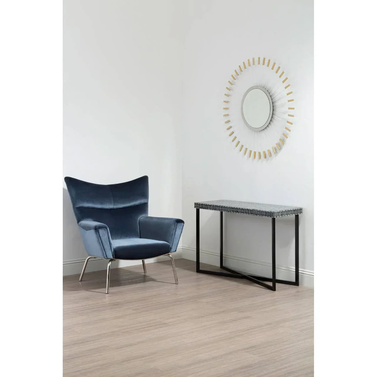 Blue velvet accent chair beside modern console table and round wall mirror in bright room
