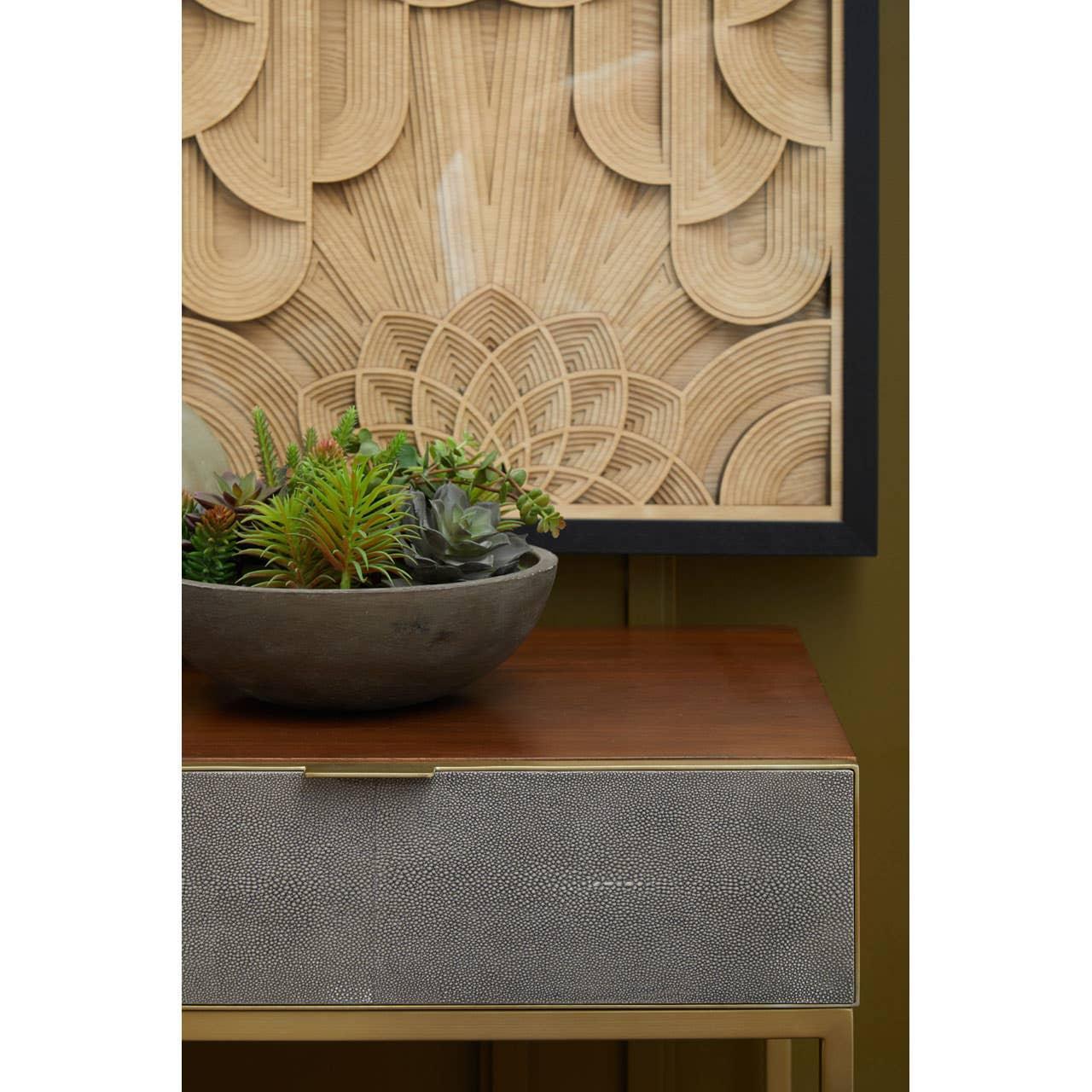 Modern console table with textured drawer and bowl of succulents, wood wall art background