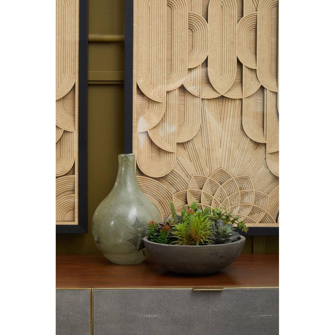 Decorative sideboard with green vase, succulent bowl, and textured wooden wall art