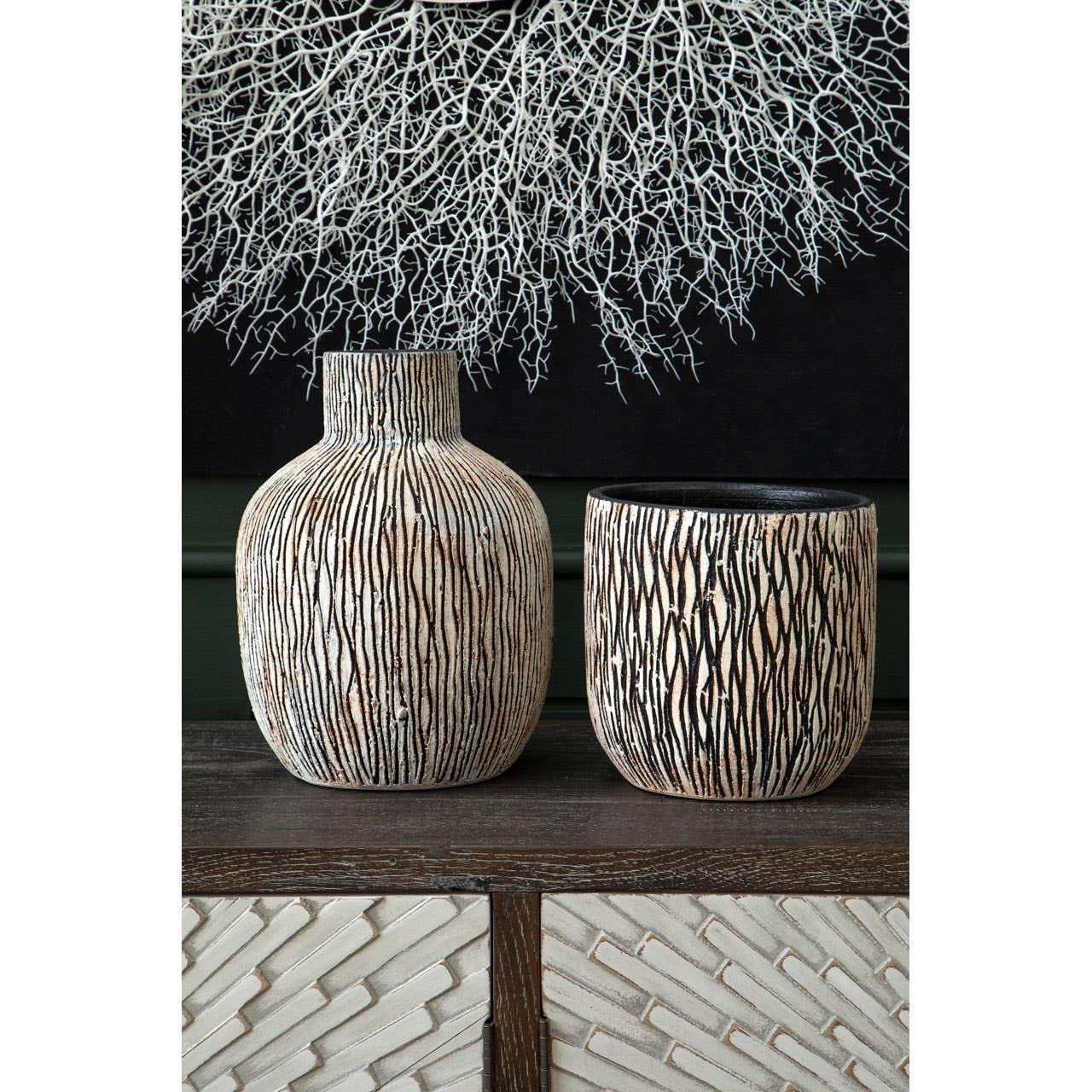 Ceramic vases with textured stripe detail on dark wood sideboard, wall art in background
