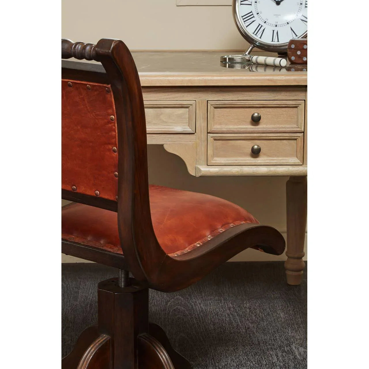 Brown leather office chair with wooden frame beside light wood writing desk with drawers