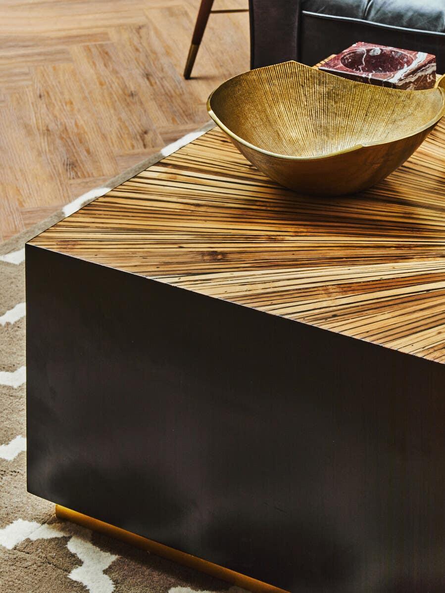 Modern wooden coffee table with geometric top and gold decorative bowl on patterned rug