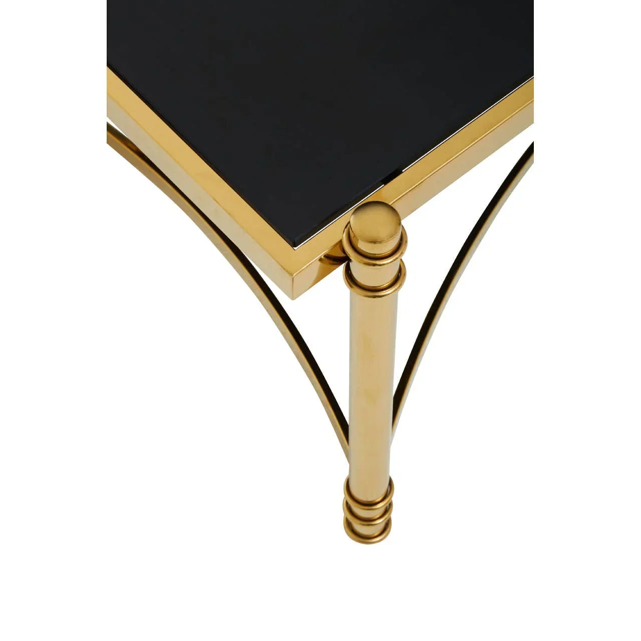 Corner of black glass coffee table with gold metal frame and decorative leg detail