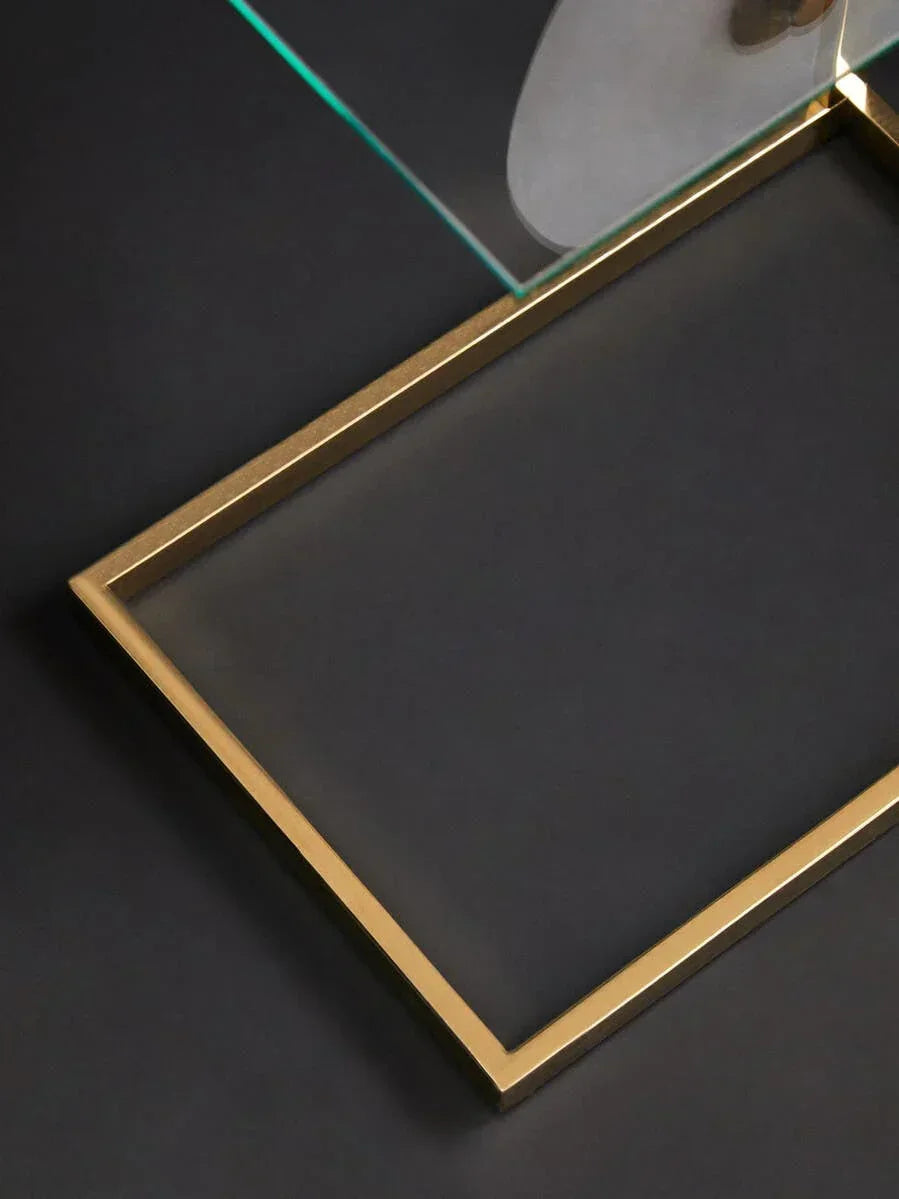 Glass coffee table with gold metal frame and black surface, corner detail view