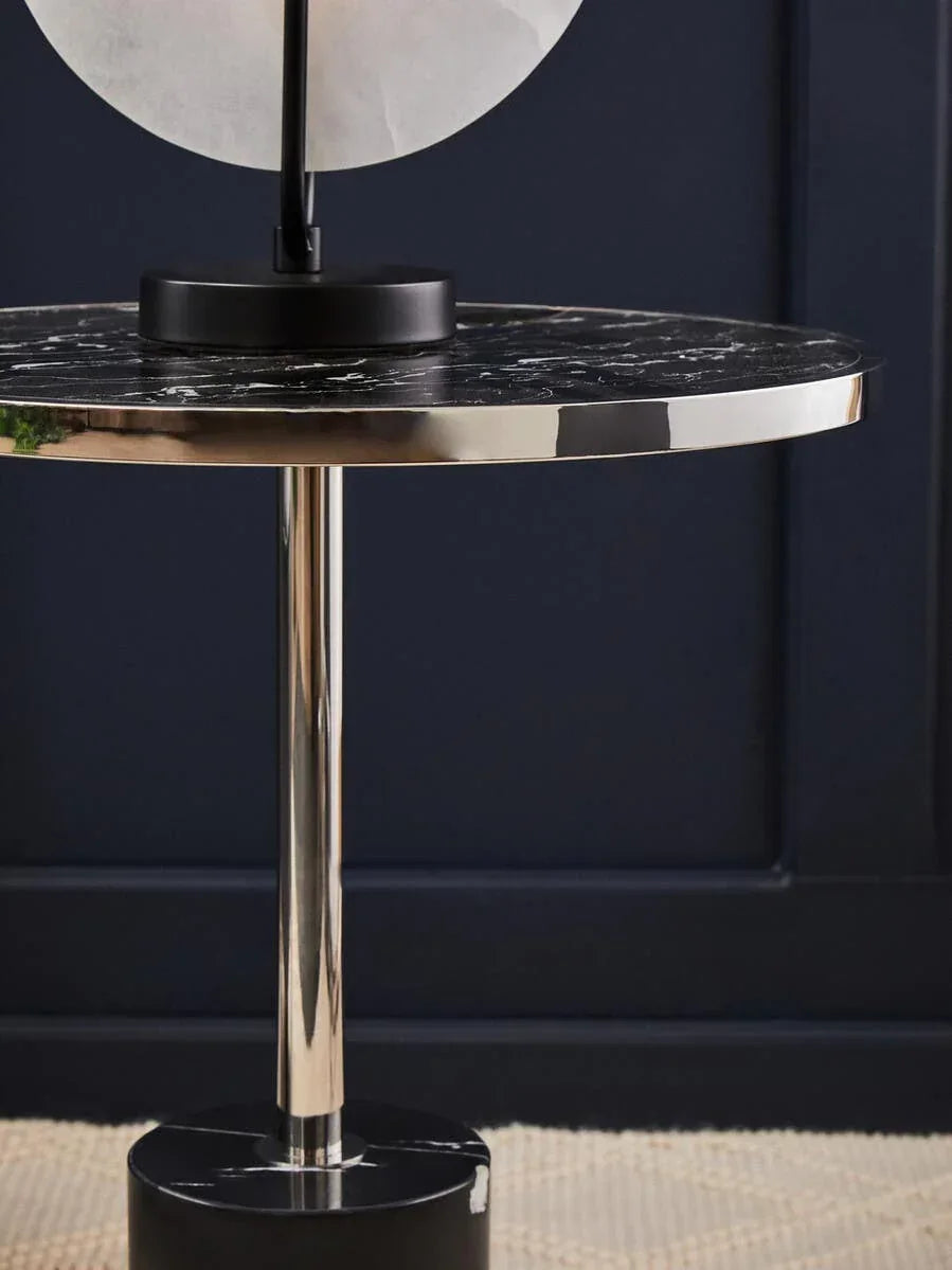 Round black marble side table with chrome pedestal base and metallic rim