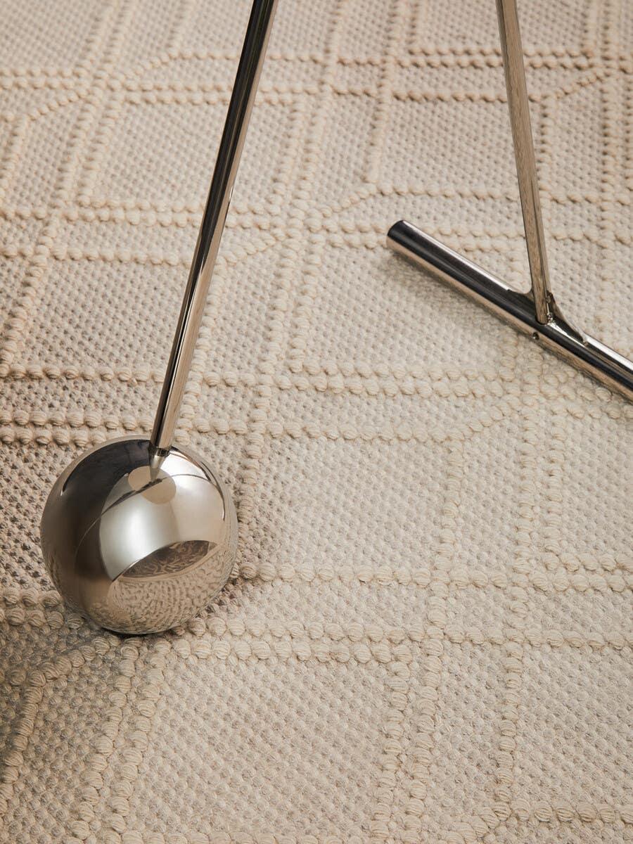 Chrome table lamp leg with round base on beige textured area rug