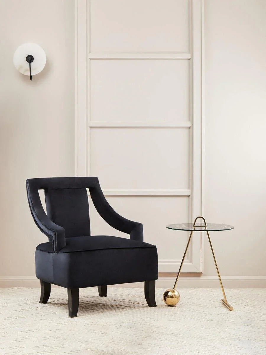 Black velvet accent chair with cutout back and gold side table in modern living room