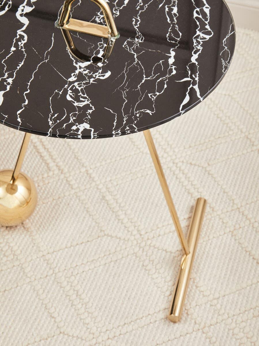 Black marble effect side table with gold tripod base on textured cream rug