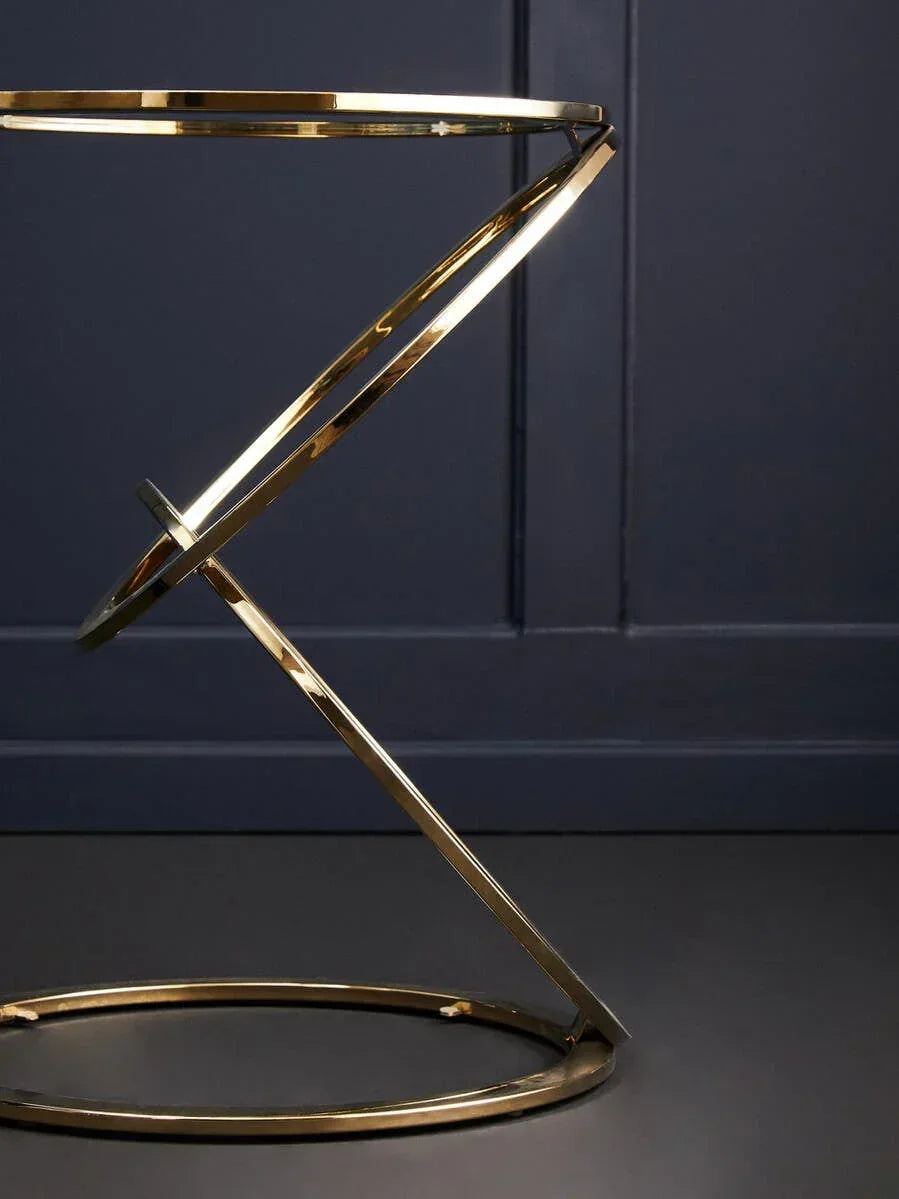 Gold metal side table with geometric base against dark wall