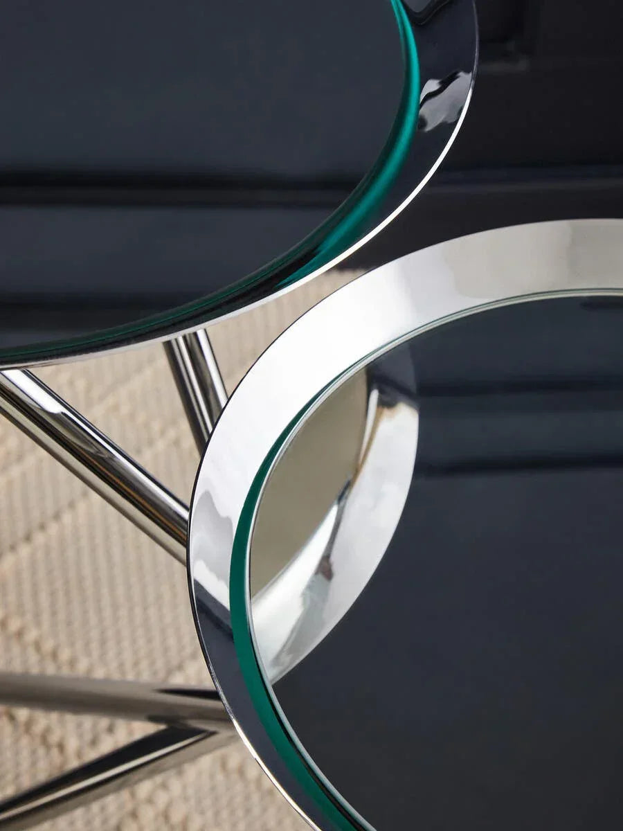 Close up of nesting glass side tables with chrome metal frame on textured rug