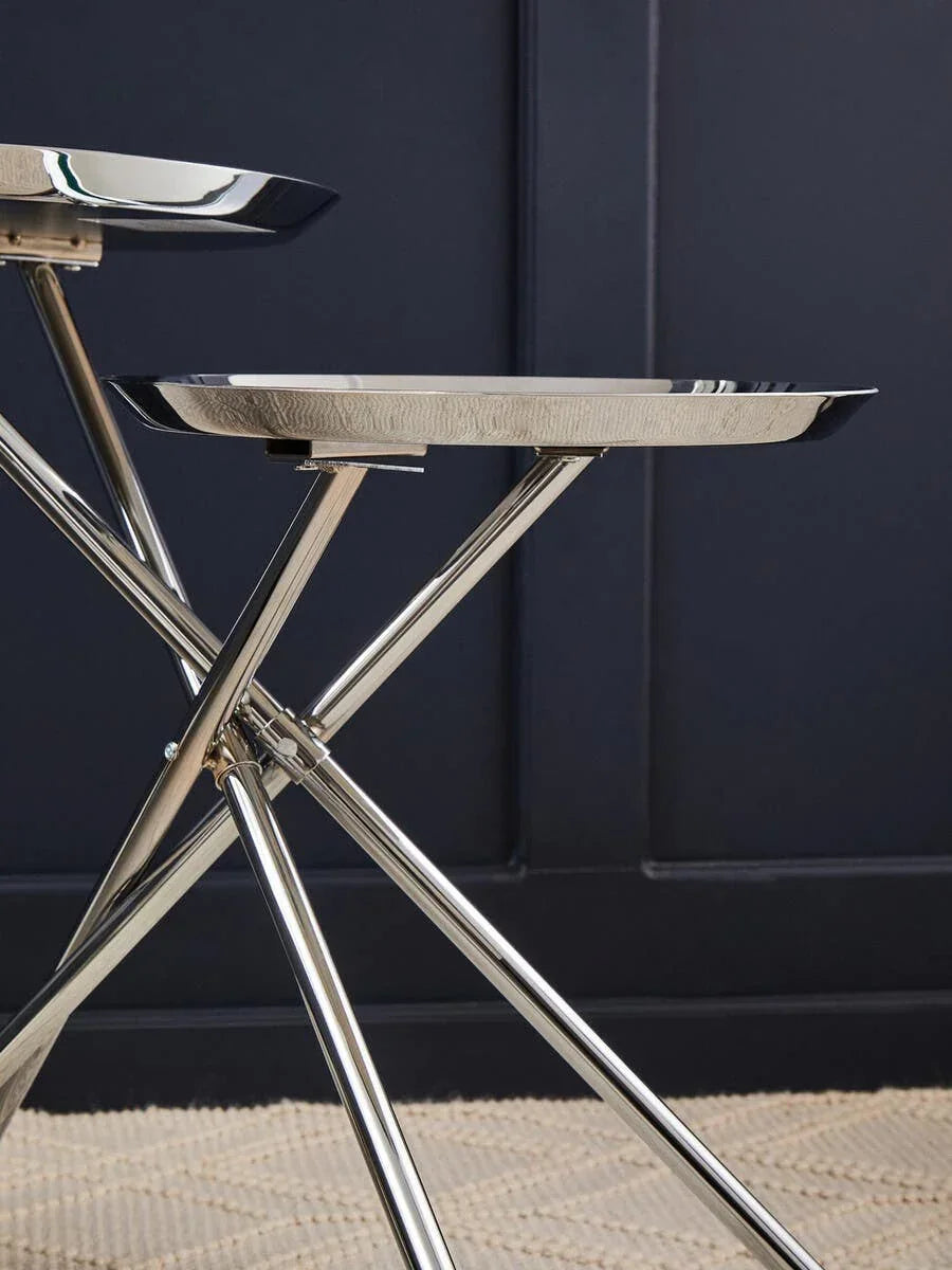 Chrome finish side table with round tray top and crossed legs on textured rug