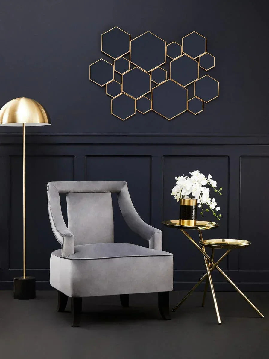 Grey accent chair with gold side table, floor lamp, and geometric wall art in modern living room