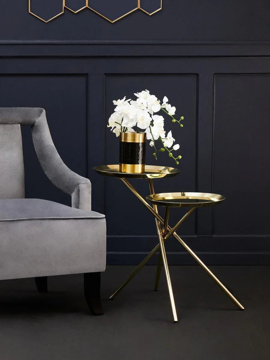 Gold metal side tables with white flowers beside grey velvet accent chair in modern living room