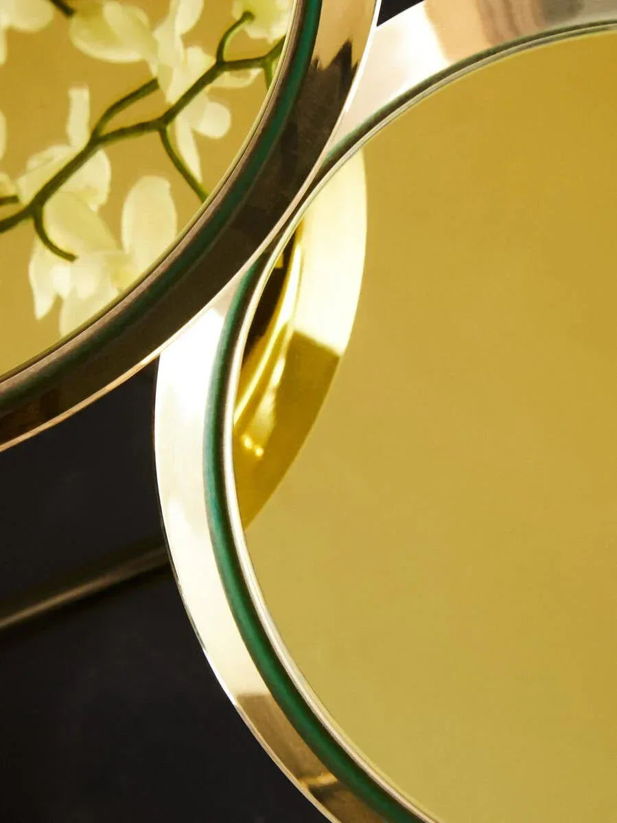 Round gold metal side tables with reflective surface and floral reflection