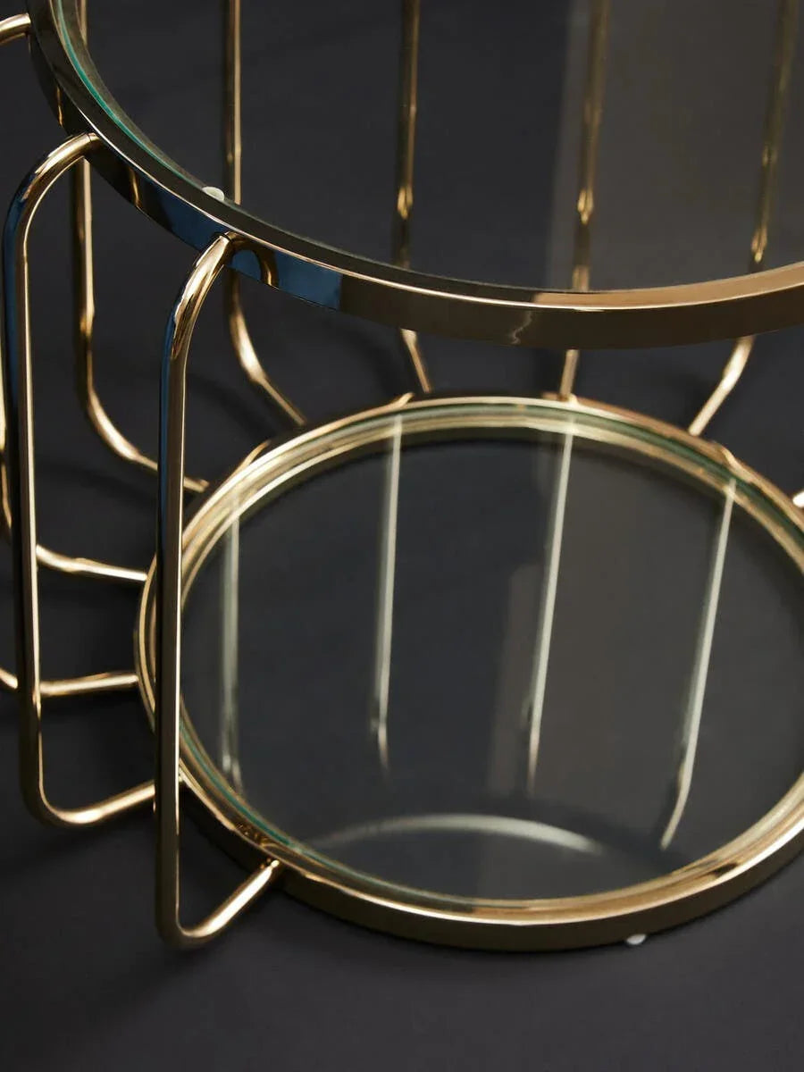 Glass coffee table with gold metal frame and round clear top on dark surface