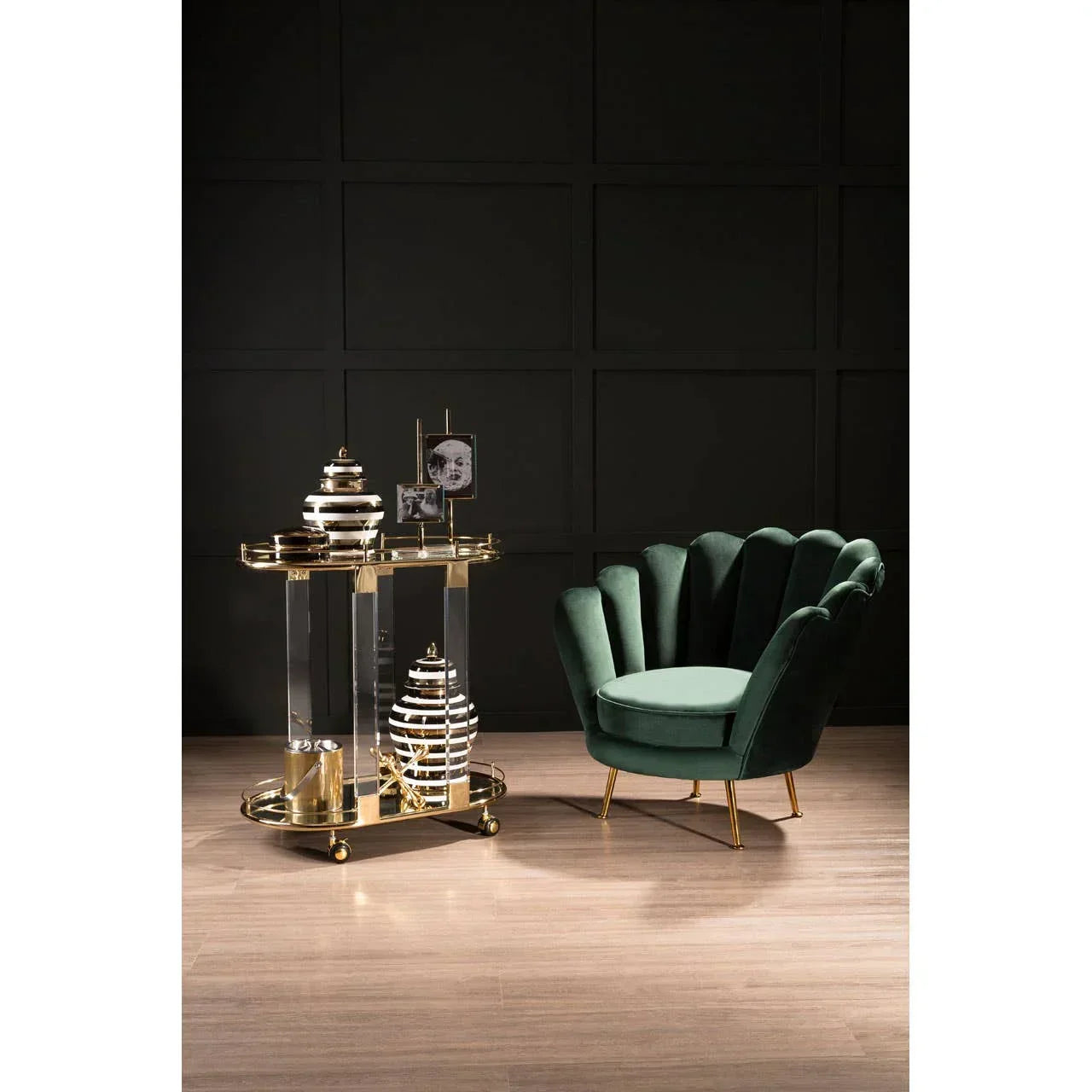 Green velvet accent chair with gold legs beside gold and glass side table in modern room