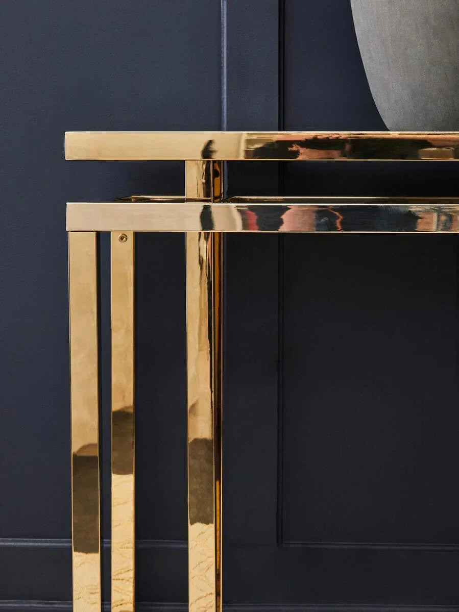 Gold metal console table with minimalist frame against dark panelled wall