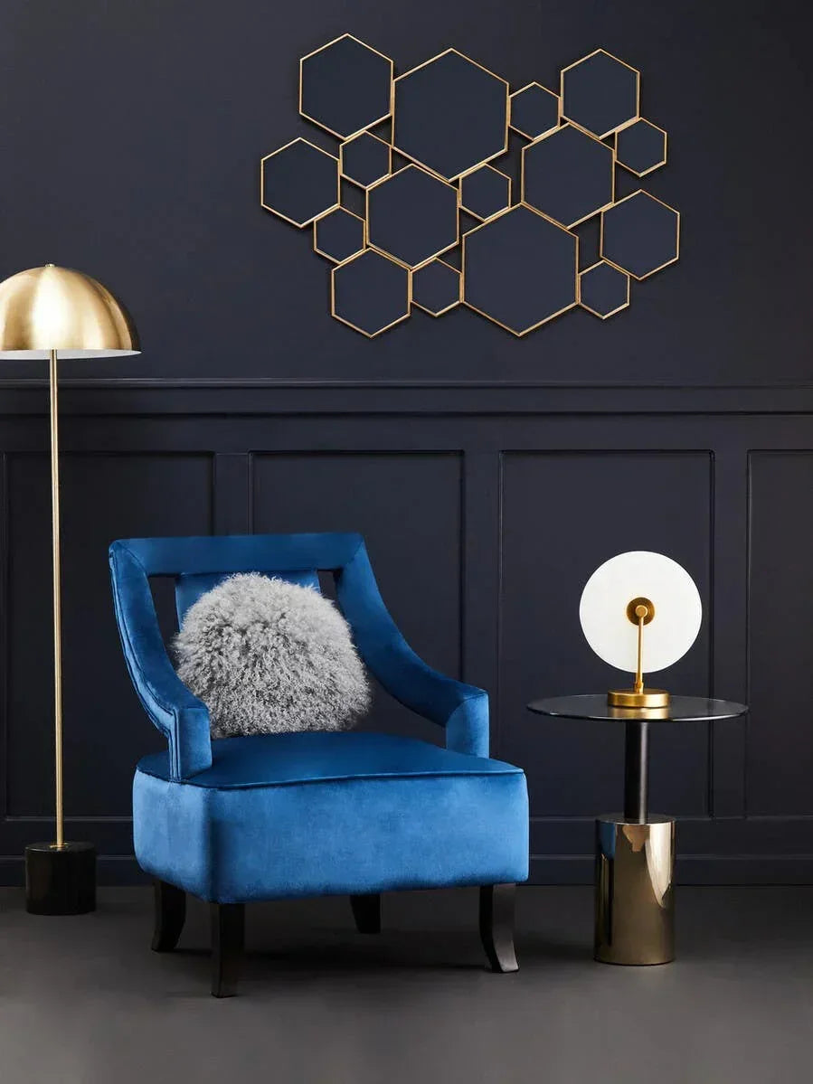 Blue velvet accent chair with grey cushion beside gold lamp and modern side table