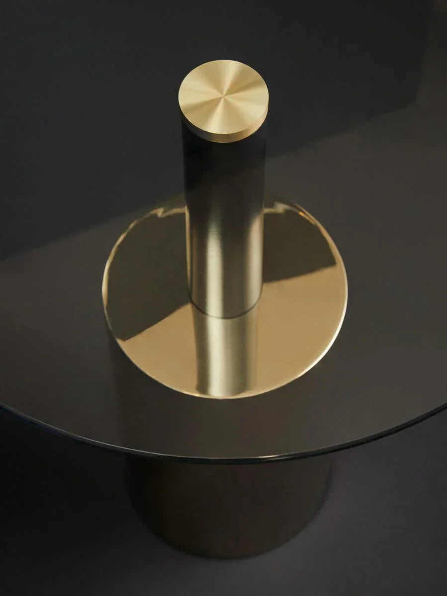 Round glass coffee table with gold metal base and central cylindrical support