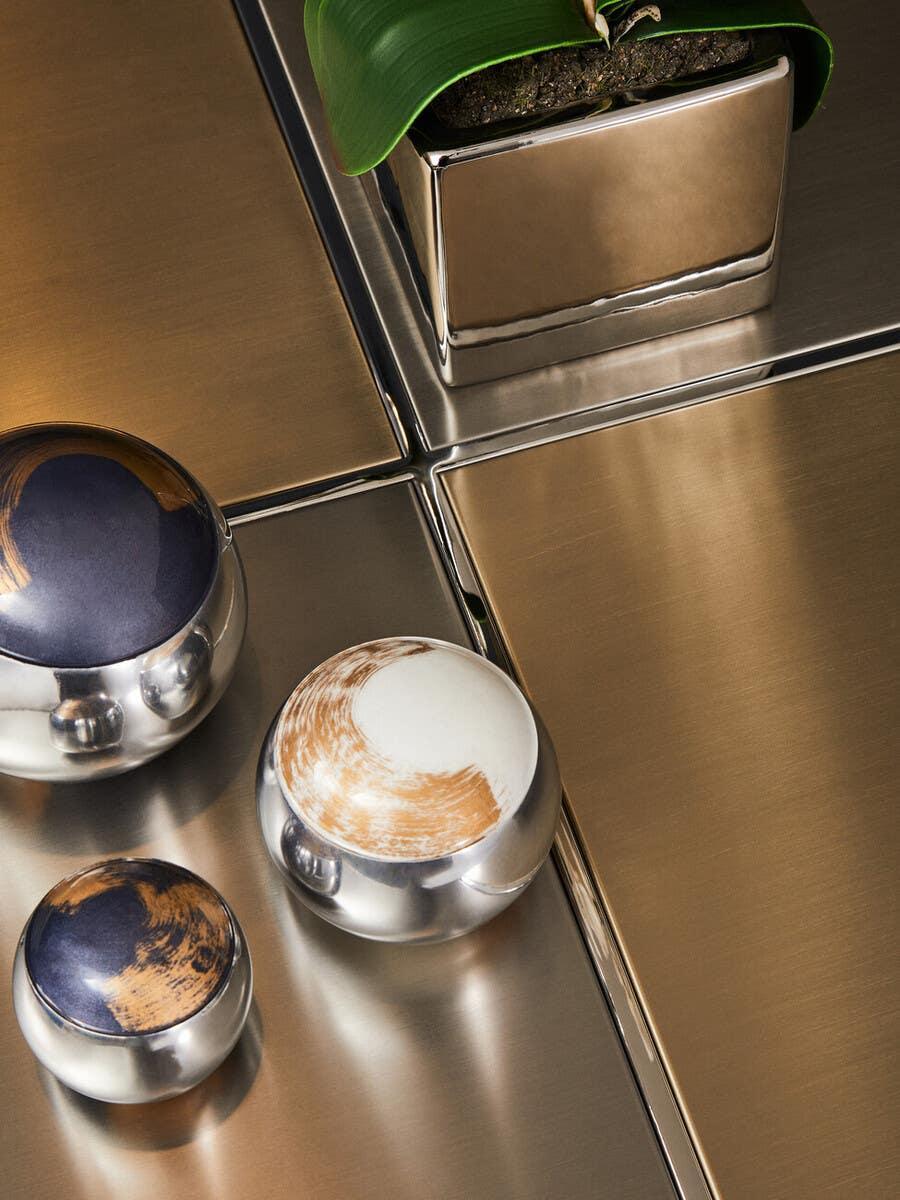 Brushed brass coffee table with decorative metal and enamel orbs and a metallic plant pot